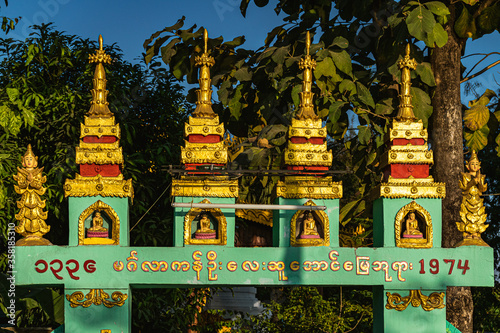 Decorative gate with little gilded stupas and Buddhist motifs in in Taungoo, Myanmar. photo