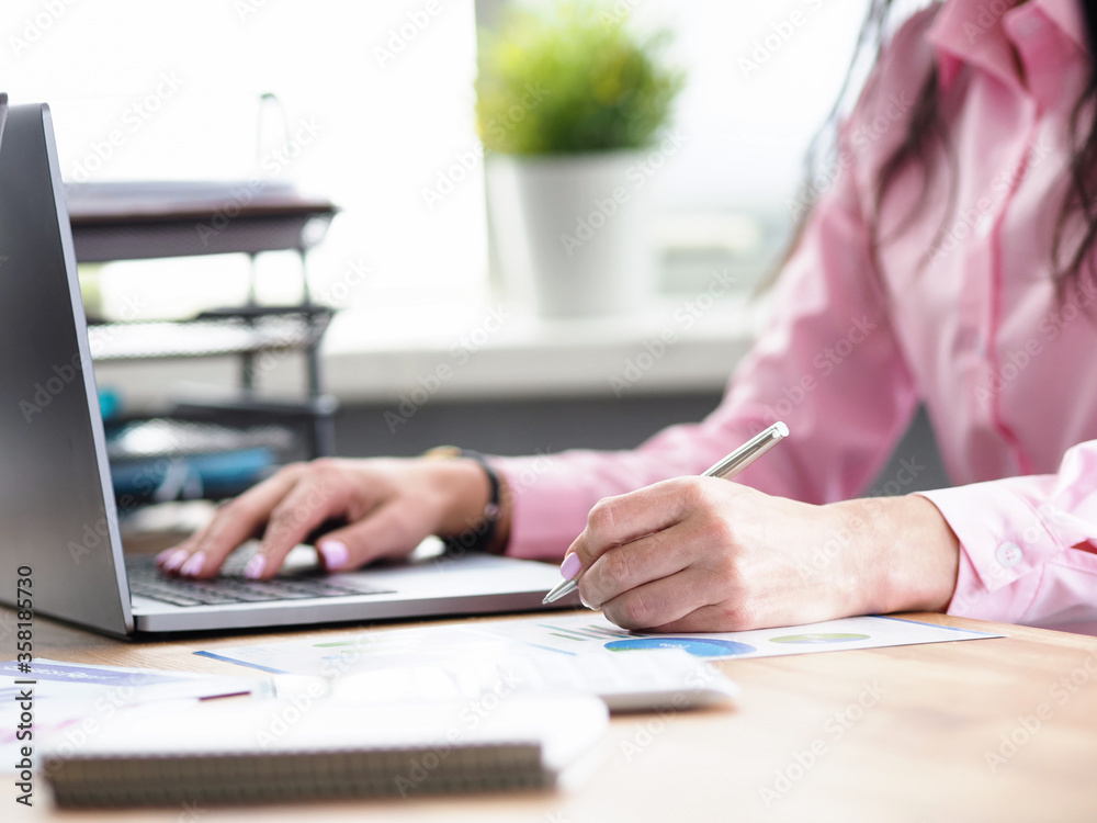 Office worker writes notes and prints on laptop Office worker writes notes and prints on laptop