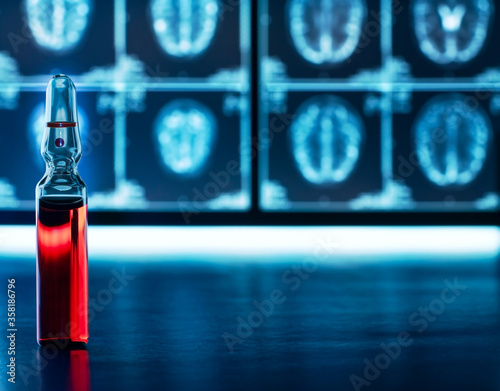 A medical ampoule with red liquid on an mri brain scan background