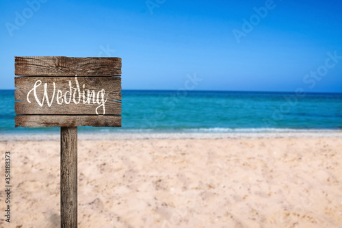 Wooden plaque with inscription Wedding on sandy beach, space for text