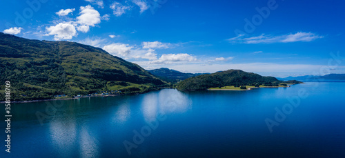 aerial image of loch linnhe on the west coast of the argyll and lochaber region of scotland near kentallen and duror showing calm blue waters and clear skies with green forest coast line