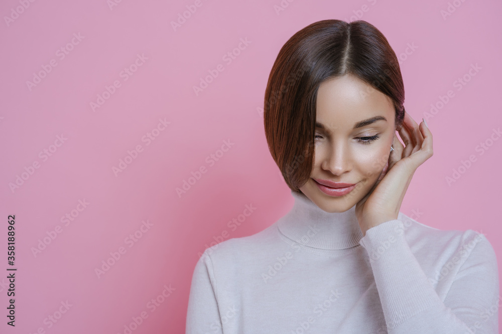 Photo of thouhtful shy young woman looks down, has dreamy expression, dressed in casual clothing, thinks about something pleasant, isolated over rosy background, blank space for your promotion Photo of thouhtful shy young woman looks down, has dreamy expression, dressed in casual clothing, thinks about something pleasant, isolated over rosy background, blank space for your promotion