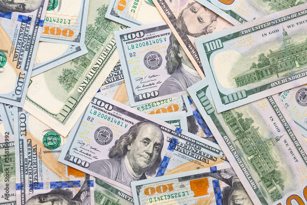 A pile of one hundred US banknotes with president portraits. Cash of new hundred dollar bills. The banlnotes are flat. Top view.