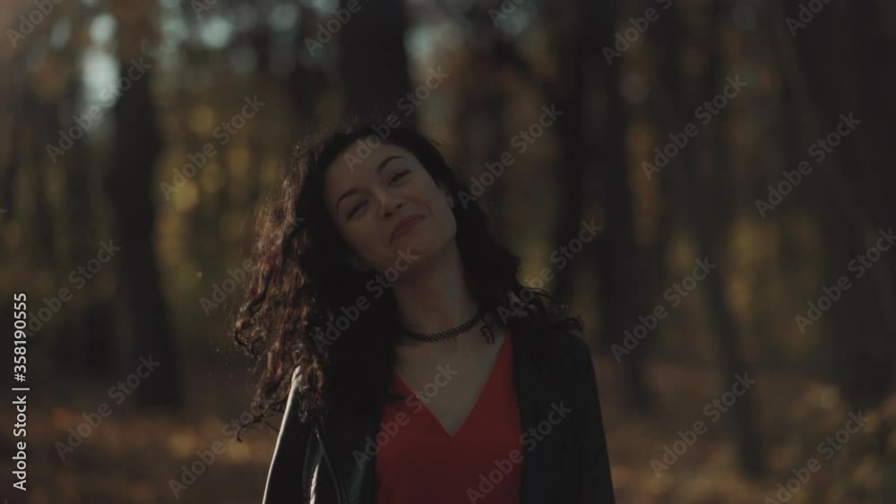beautiful curly brunette female walking in autumn park and smiling beautiful curly brunette female walking in autumn park and smiling