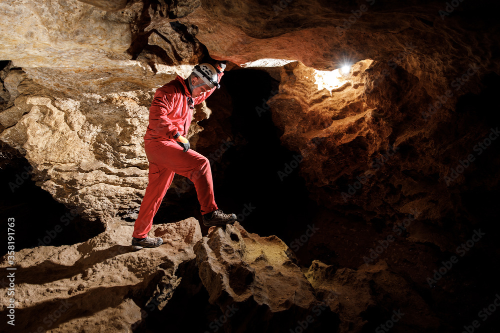 Man walking and exploring dark cave with light headlamp underground ...