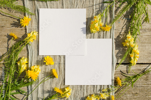 Summer stationery mockup scene with with yellow flowers on a old wood background in rustic style and natural. Mockup card for greeting card or wedding invitation. Flat lay, top