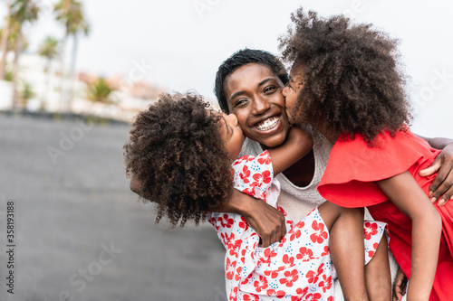 African sisters twins kissing mother on the beach - Black family having fun outdoor during summer vacation - Love, real people and travel concept - Main focus on mum face photo