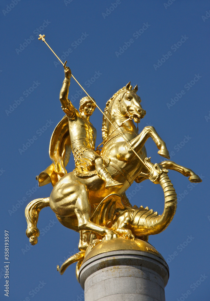 Obraz premium Gold sculpture of St. George slaying a dragon atop a column in Freedom Square, Tbilisi, Georgia