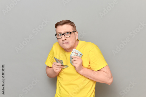 Portrait of funny greedy man holding money in hands and counting cash photo