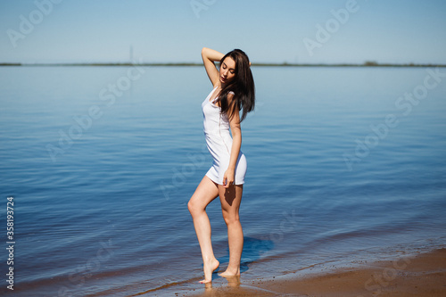Fototapeta Naklejka Na Ścianę i Meble -  Young sexy lady in the white dress standing in the warm water.