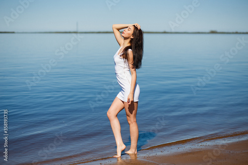 Young sexy lady in the white dress standing in the warm water.