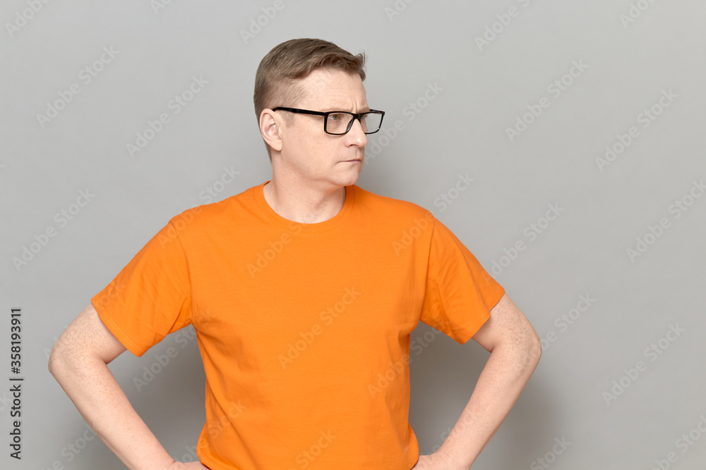 Portrait of serious mature man with glasses, wearing orange T-shirt Portrait of serious mature man with glasses, wearing orange T-shirt