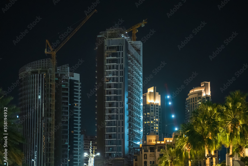 New high rise building construction site in Dubai at night. Fast Dubai development concept.