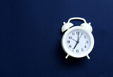 A beautiful vintage white alarm clock shows 7 o'clock in the morning. Time to Wake up and have Breakfast. Space for text. Selective focus. Copy space