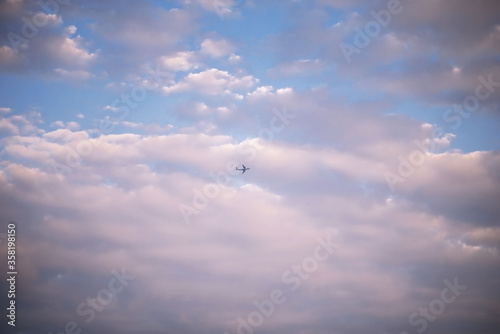 plane against the sky around a lot of beautiful clouds with pink light background