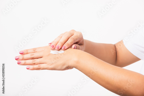 Closeup young Asian woman applying lotion cosmetic moisturizer cream on her behind the palm skin hand  studio shot isolated on white background  Healthcare medical and hygiene skin body care concept