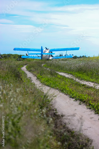 A yellow flower in a field. Aeroplane in clear summer field: commercial and agricultural helicopter service