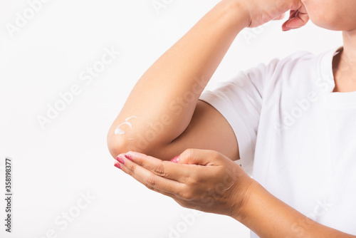 Closeup young Asian woman applies lotion cream on her elbow  studio shot isolated on white background  Healthcare medical and hygiene skin body care concept