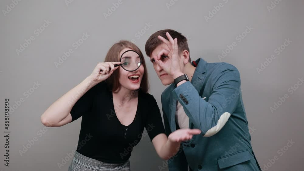 Wonder looking through magnifying glass, curious, suspicious, scared in shock with a surprise face, afraid and excited fear expression. Young attractive couple boyfriend girlfriend two people Wonder looking through magnifying glass, curious, suspicious, scared in shock with a surprise face, afraid and excited fear expression. Young attractive couple boyfriend girlfriend two people