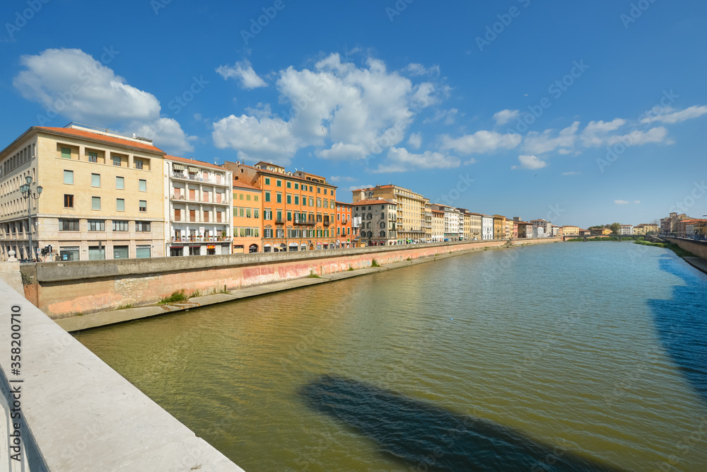 Colorful buildings line the banks of the Arno River in the Tuscan city of Pisa, Italy.
