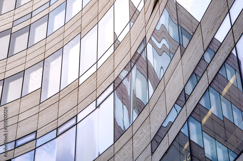 Close up contrast detail with curvature shape and reflected glass facade with rectangular windows grid frame system of modern office building. Abstract Architectural Geometry elements background.