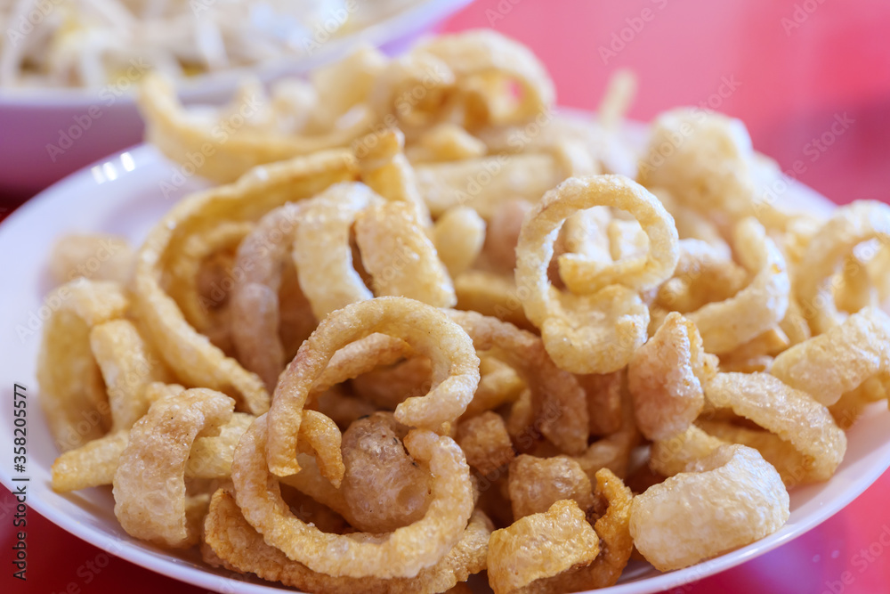 Pile of deep fried or bake pork snack, pork rind, pork scratching or pork crackling on white dish. Pile of deep fried or bake pork snack, pork rind, pork scratching or pork crackling on white dish.