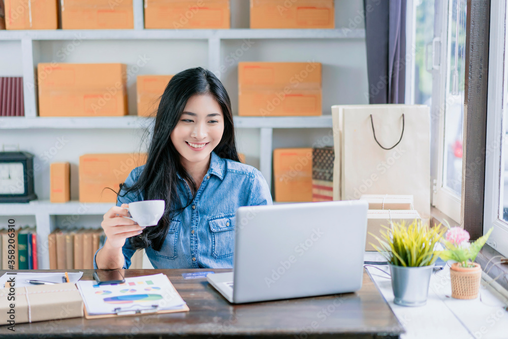 Asian beautiful woman having coffee break relax happy relief working from home office in isolation quarantine, smiling working on desk using computer laptop typing planning strategy business company Asian beautiful woman having coffee break relax happy relief working from home office in isolation quarantine, smiling working on desk using computer laptop typing planning strategy business company