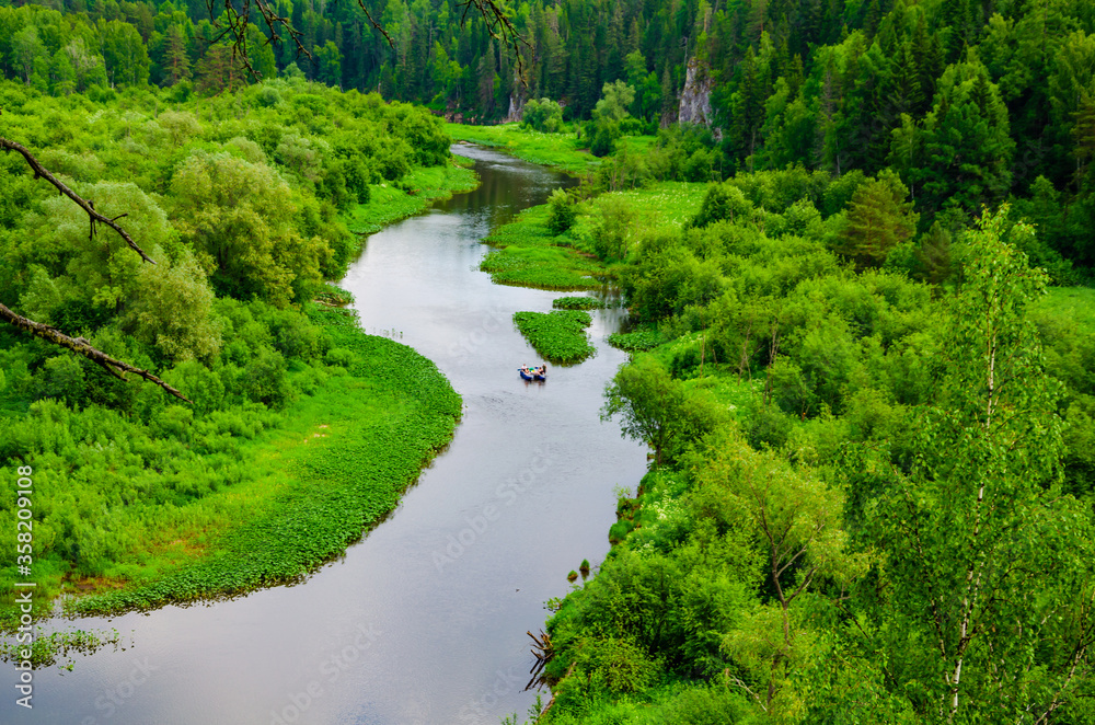 People on an inflatable raft float on the river among the mountains and forests in summer. People on an inflatable raft float on the river among the mountains and forests in summer.