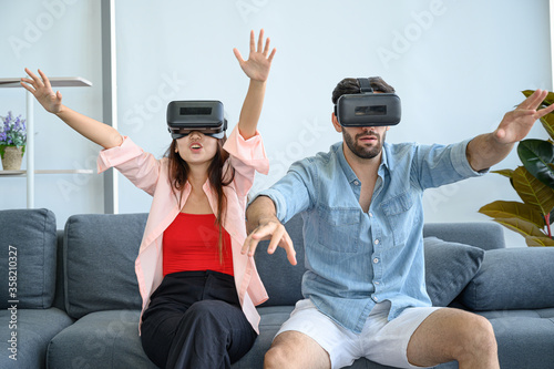 Couple lovers enjoy playing VR game together at home.