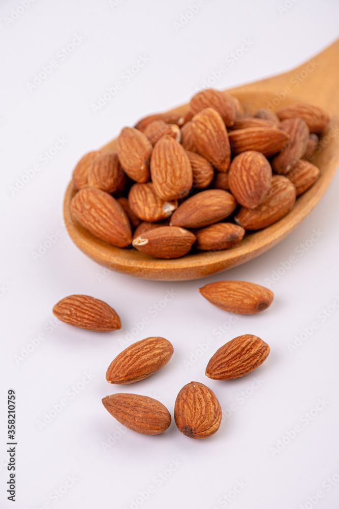 almonds and wooden spoon on white background almonds and wooden spoon on white background