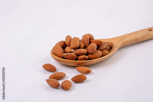 almonds and wooden spoon on white background
