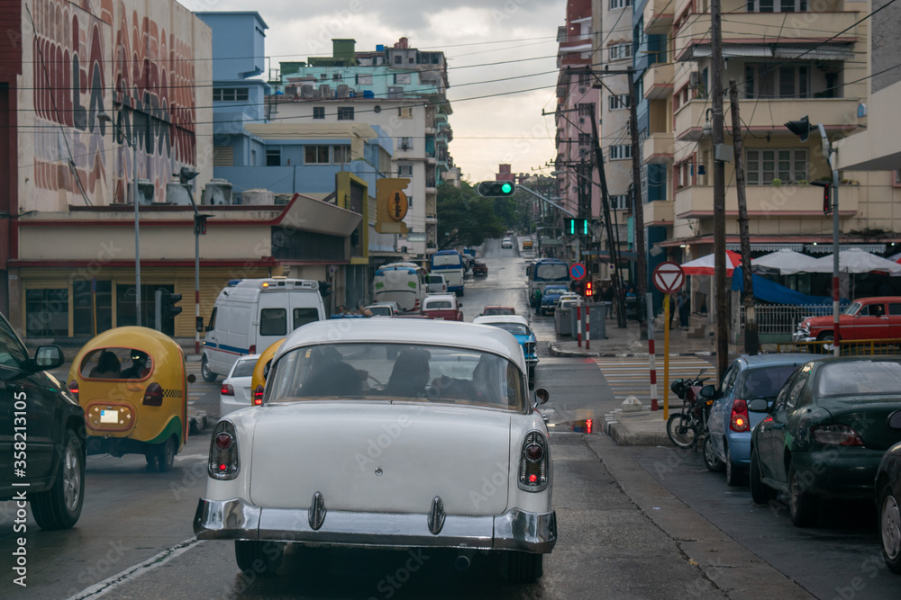 Naklejka premium Nostalgic retro and modern imported cars clash in downtown Havana, Cuba.