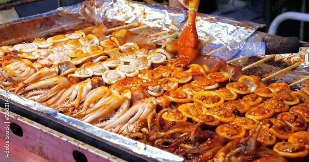 Spicy of Grilled squid satay with fire. Grilled squid on skewers, Delicious street food, Burning food, Blow torch cooking.