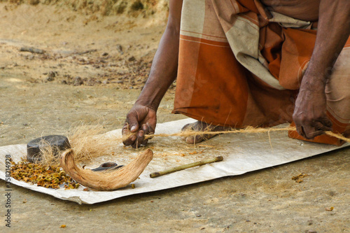 Man twisting coconut husk fiber (coir) into twine, Sri Lanka photo