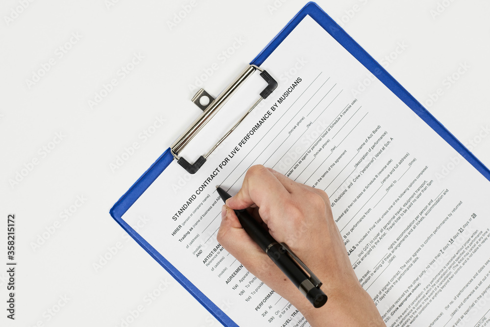 Signing standart contract for live performance by musicians. A musician filling live performance contract Signing standart contract for live performance by musicians. A musician filling live performance contract