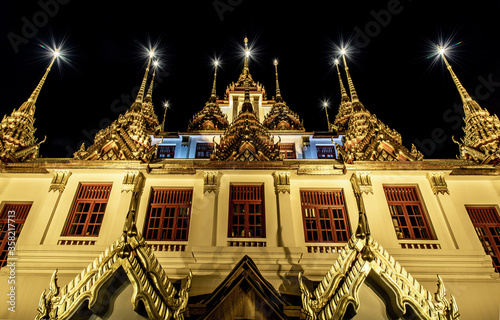 Golden shining Loha Prasat (Metal Castle) lit up at night, a pyramid shaped Buddhist temple from 1846 for meditation in Wat Ratchanatdaram, Here It is the most tourist destination landmark. photo