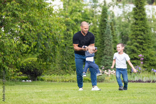 Cute cheerful two boys brother child with father play outdoors in park. Happiness and harmony of family life. Great family vacation.
