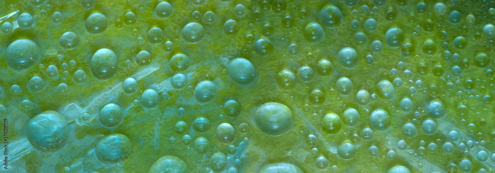 White-green and translucent green spheres of different diameters are located on a malachite-green background. Cosmic abstraction.