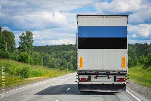 A truck with the national flag of Estonia depicted on the back door carries goods to another country along the highway. Concept of export-import,transportation, national delivery of goods