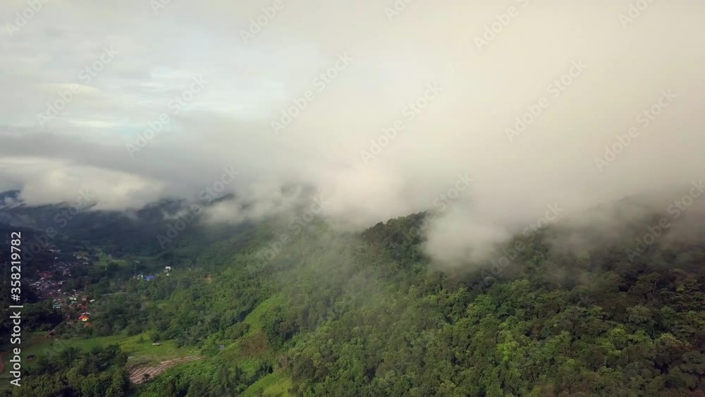 Aerial view flying thru the morning rain cloud covered tropical rain forest mountain landscape during the rainy season on the Doi Phuka Mountain reserved national park the northern Thailand Aerial view flying thru the morning rain cloud covered tropical rain forest mountain landscape during the rainy season on the Doi Phuka Mountain reserved national park the northern Thailand