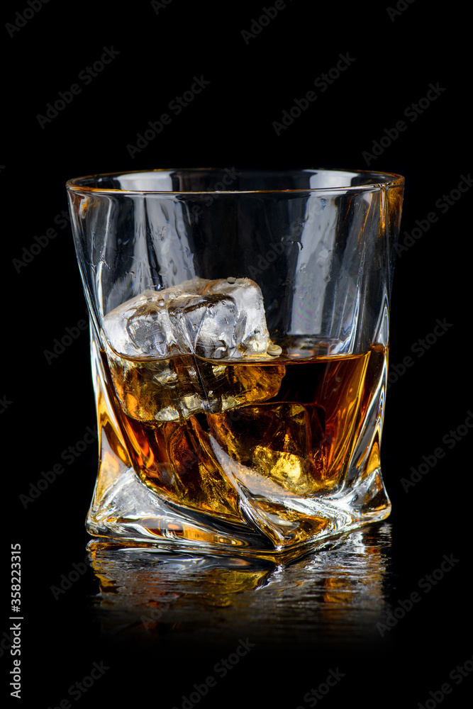Glass of whiskey with cube ice on black background Glass of whiskey with cube ice on black background