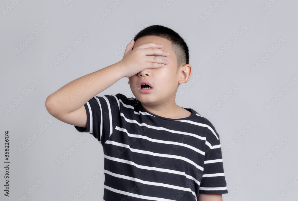 Asian boys studio portrait on gray background with hand on head for pain in head because stress. Suffering migraine. Asian boys studio portrait on gray background with hand on head for pain in head because stress. Suffering migraine.
