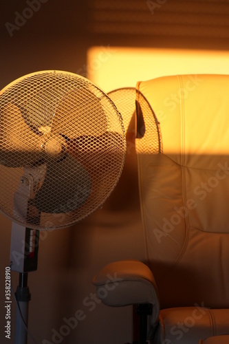 cooling by a fan in the summer heat while resting in an armchair
