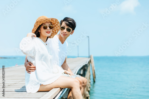Honeymoon romantoc couple hugging and sitting on wood bridge and enjoys their tropical holiday. Love concept. © Charnchai saeheng