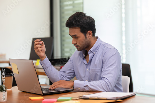 Young business indian man working with laptop thinking business plan