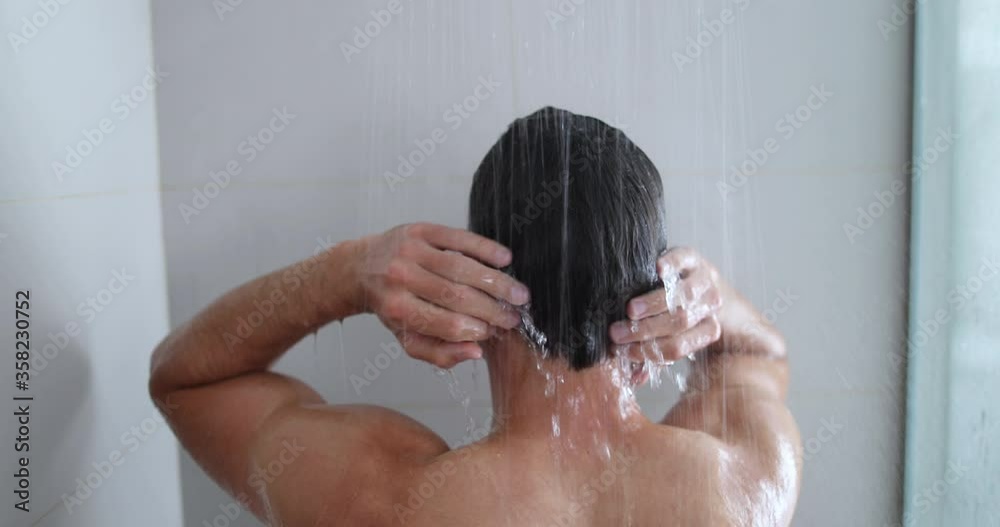 Stockvideo Man taking a shower enjoying showering under water falling