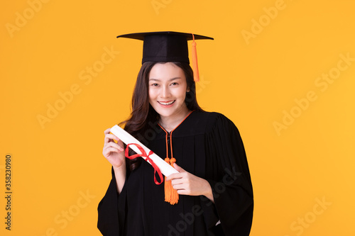 Happy Graduate asian woman in cap and gowm holding Certificated photo