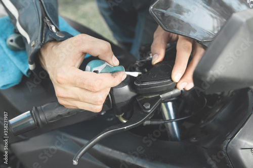 Man repairing his motorcycle in the outdoors.