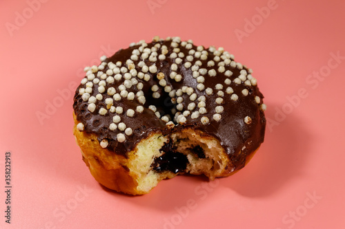 Картината върху платно Bitten tasty chocolate donut on a pink background
