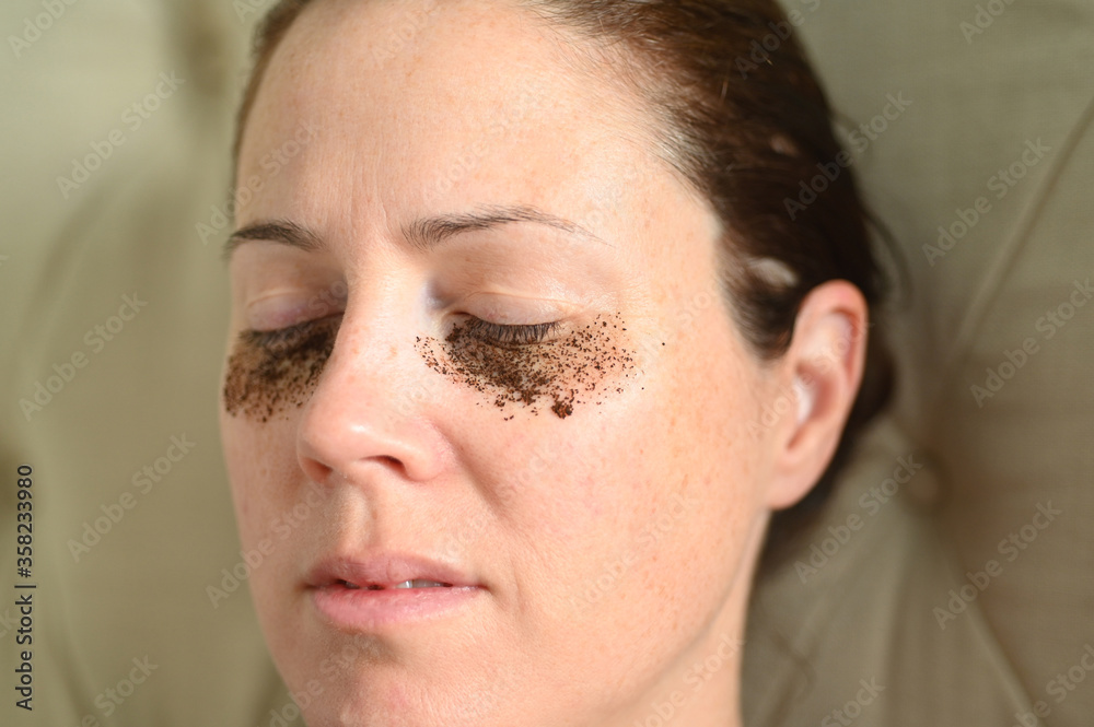 Fototapeta premium Woman relaxing at home with coffee grounds on her face